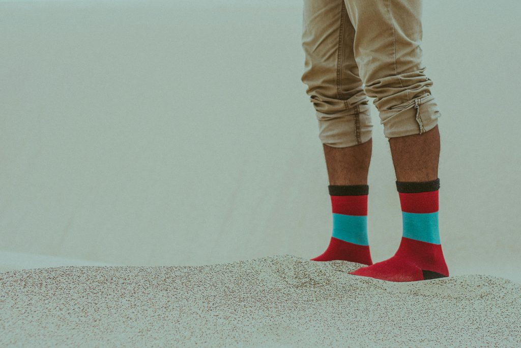 Person wearing bright socks stands on sandy dunes in Mexico. Vibrant footwear contrasts with neutral landscape.