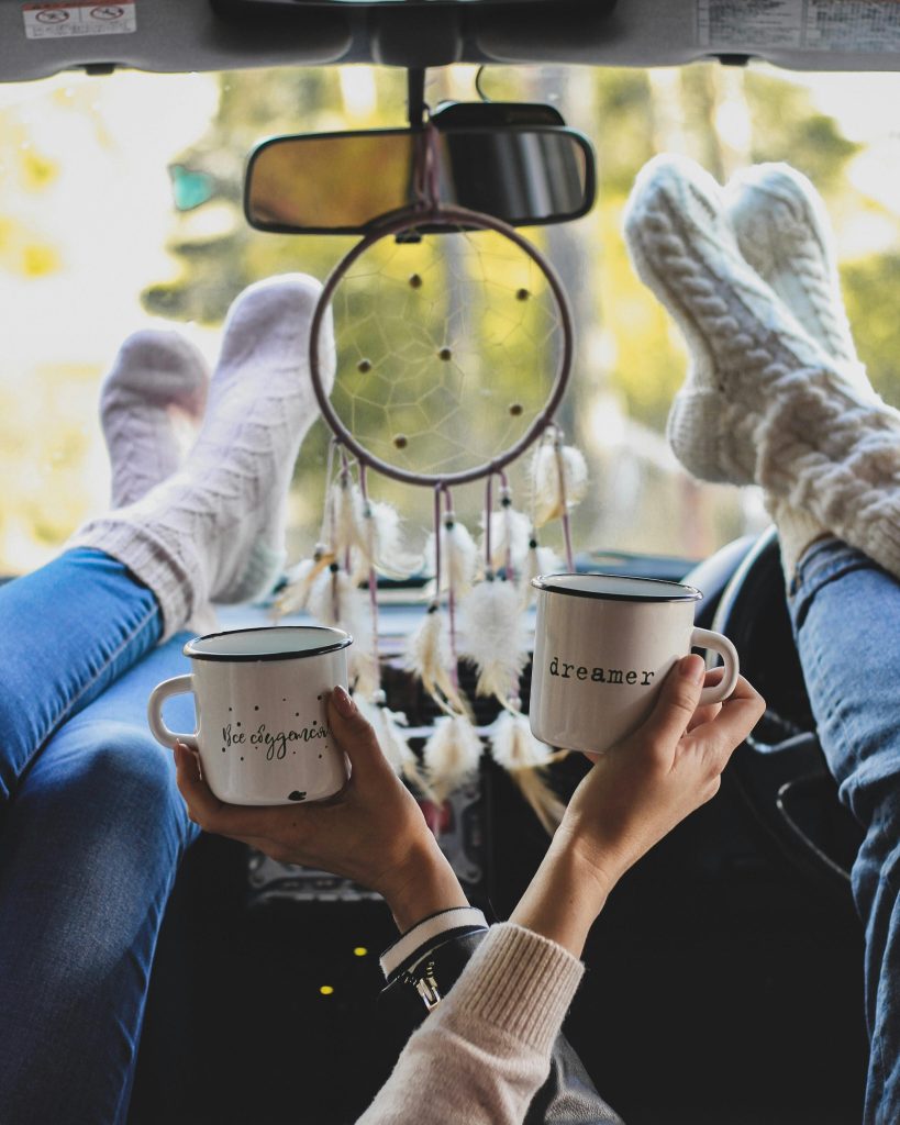 Relaxing with mugs in car interior, feet on the dashboard, cozy socks.